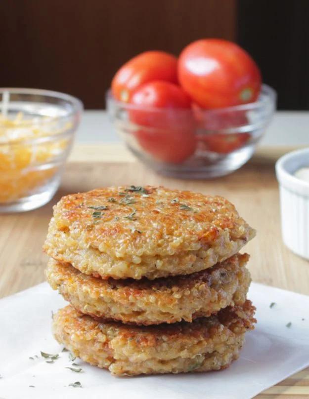 Quinoa veggie burgers with sun dried tomato and mozzarella stacked on buns beside a skillet on the counter