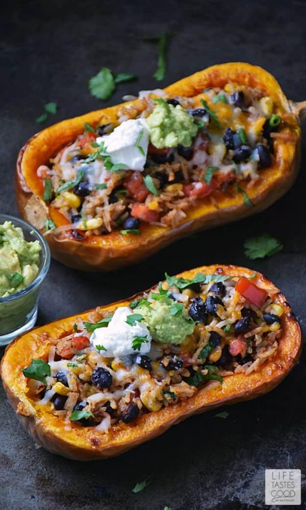 Stuffed butternut squash halves filled with seasoned rice and vegetables on a dark baking tray with guacamole