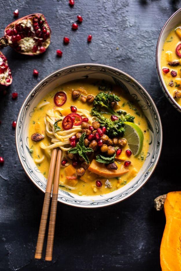 Bowl of golden Thai pumpkin laksa with noodles, greens, chickpeas and pomegranate seeds, chopsticks on top