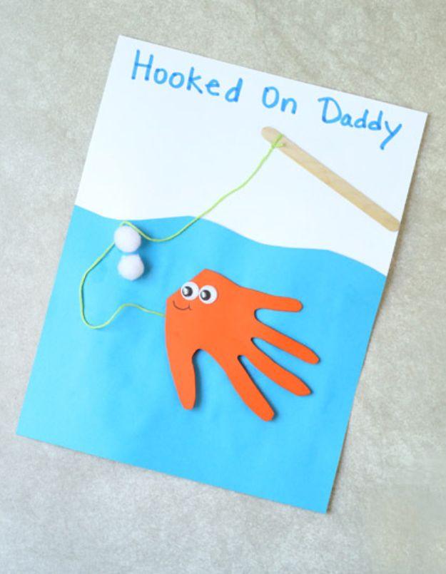 Hooked on Daddy card with an orange handprint fish in a blue paper sea and a popsicle stick fishing rod