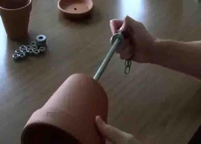 Sliding the bigger flower pot over the rod to make the DIY flower pot heater