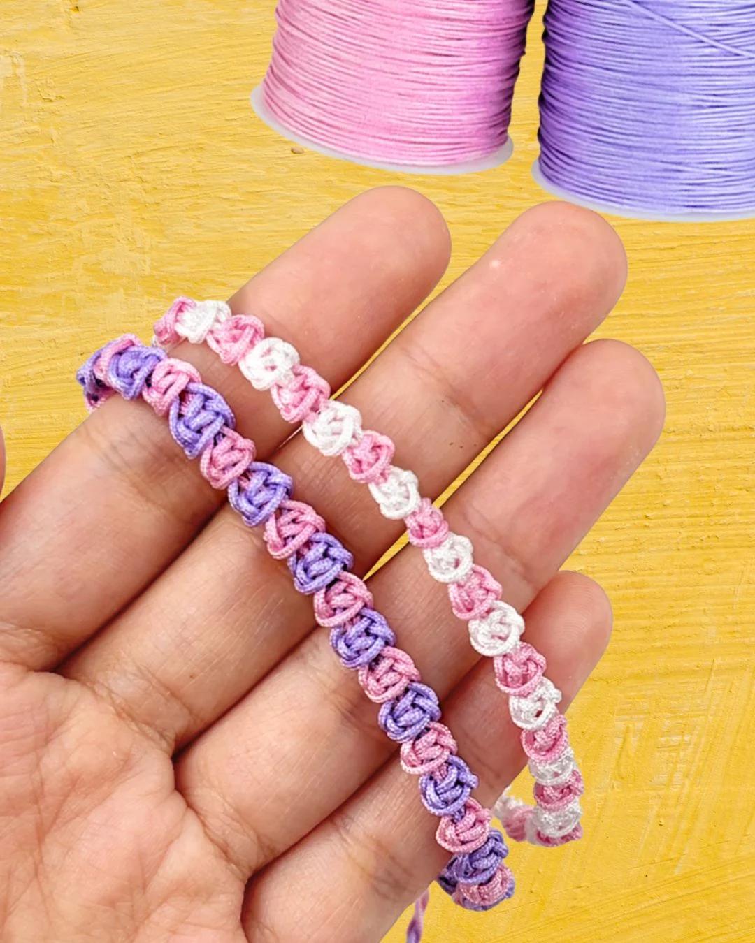 A finished DIY macrame bracelet in pink and violet cord, tied on a wrist to show the rose knot pattern up close