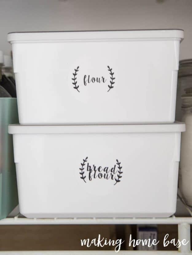 Two stacked white lidded IKEA food storage boxes labeled flour and bread flour in script on a wire pantry shelf