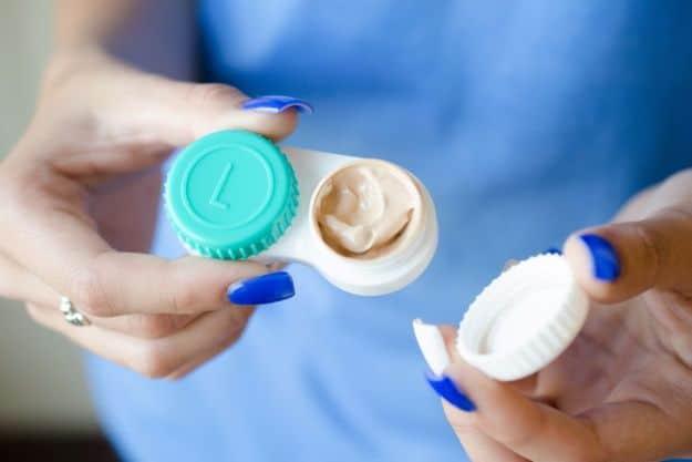 Storing liquid cosmetics in a contact lens case, a teal and white case being opened in a woman's hands