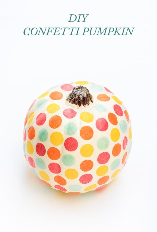 White craft pumpkin covered in red, orange, yellow and mint paper confetti dots on a white background