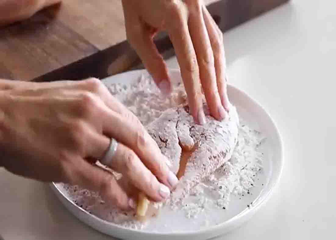 Dredging the chicken breasts on the flour mixture