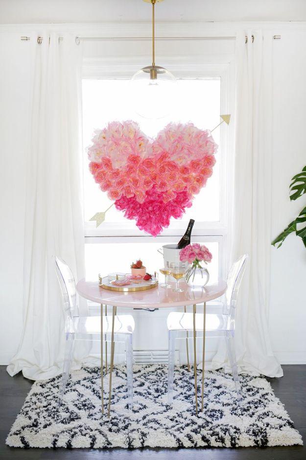 Heart of pink faux blooms shading pale at the top to deep at the base, a gold arrow through it, hung in a bright window