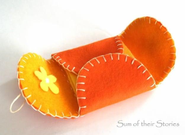 A folding felt needle case opened flat, pins and needles stuck through the pages, blanket stitched edge in floss