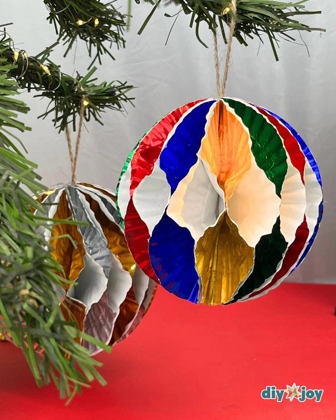 DIY Holiday Decor - two finished cupcake liner ornaments hanging from a pine garland strung with fairy lights