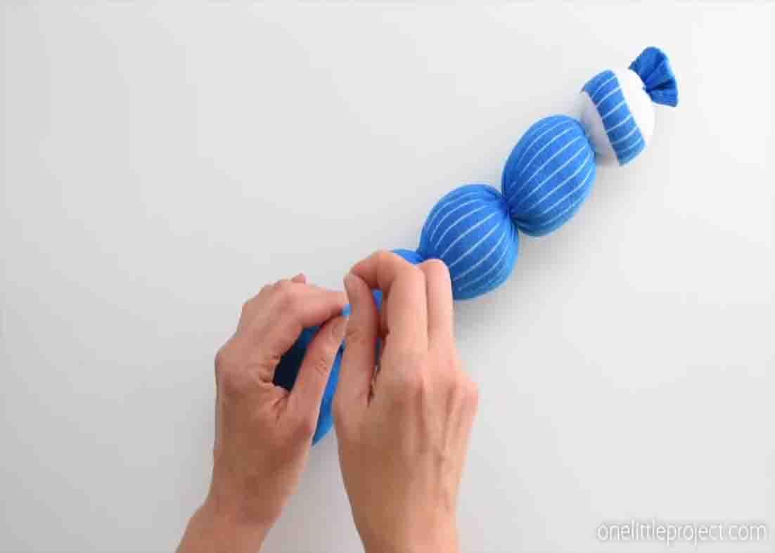 Finishing the sock toy worm by tying it with elastics
