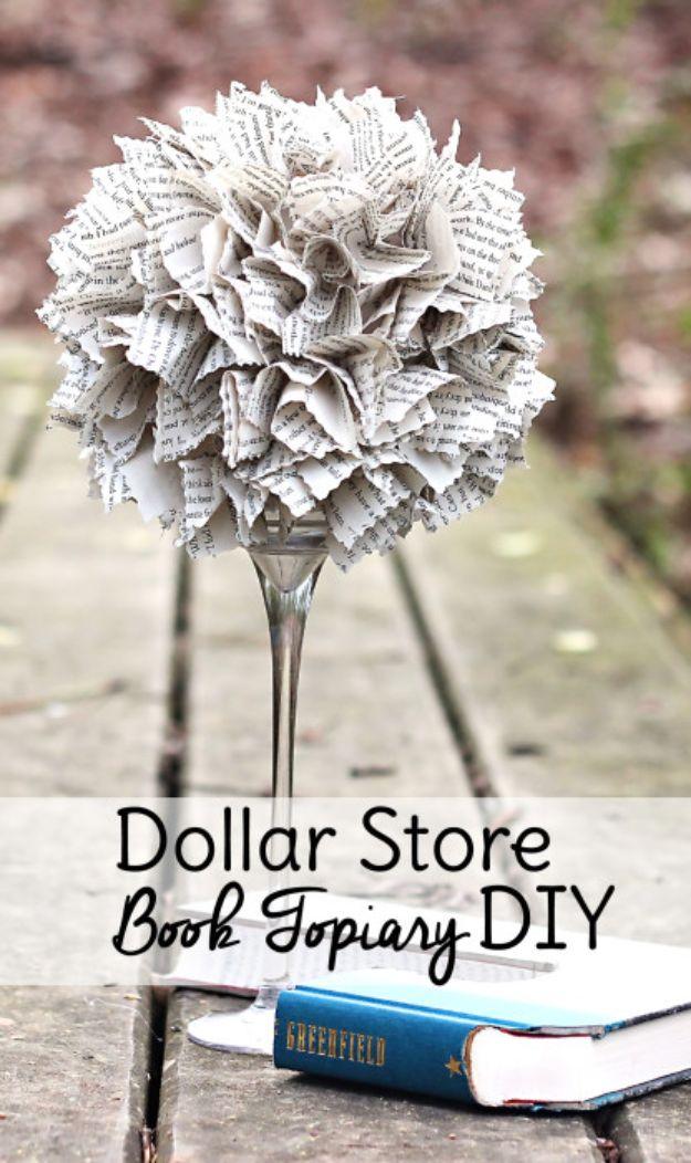 Book topiary, a ball of ruffled printed book pages set in a tall glass candle holder beside a blue hardback