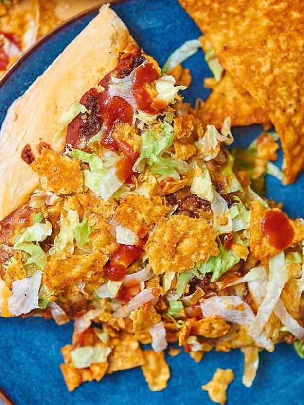 Taco pizza slice topped with seasoned beef, shredded lettuce, salsa and crushed Doritos on a blue plate