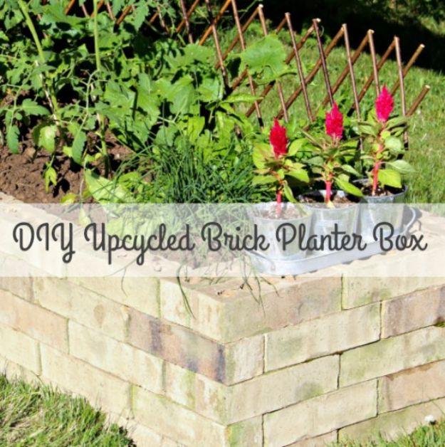 Low planter box built from stacked brick, planted with red celosia and green foliage, edged by a lawn
