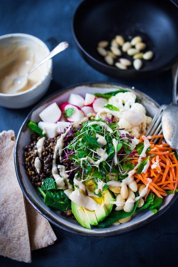 Lentil veggie bowl with lentils, radish, carrot, cauliflower, avocado and sprouts under a tahini drizzle