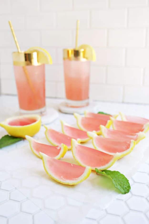 Pink lemonade jello shots in small clear plastic cups, pale pink and set firm, ready for a summer party
