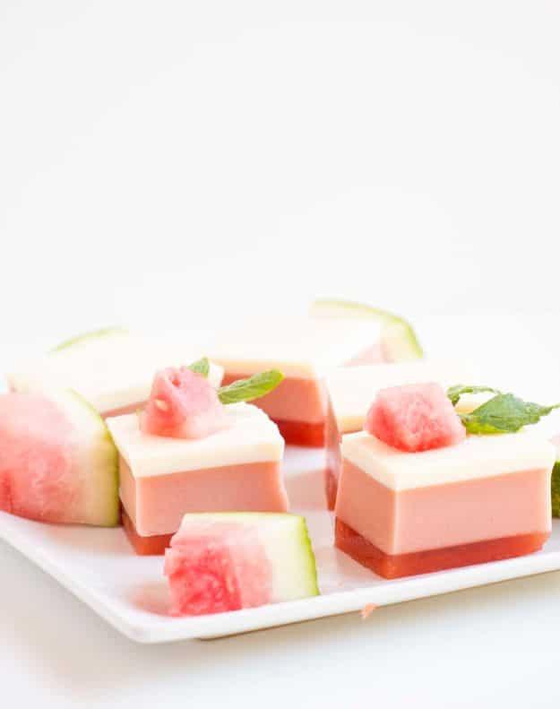 Three layer watermelon gelatin cubes with pink, white and green stripes arranged on a white serving plate