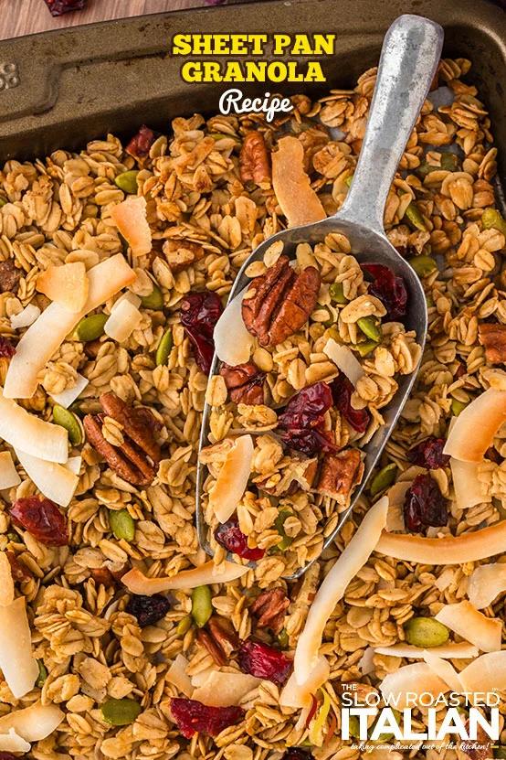 Sheet pan of golden granola with pecans, coconut flakes and dried cranberries and a metal scoop, with recipe title text