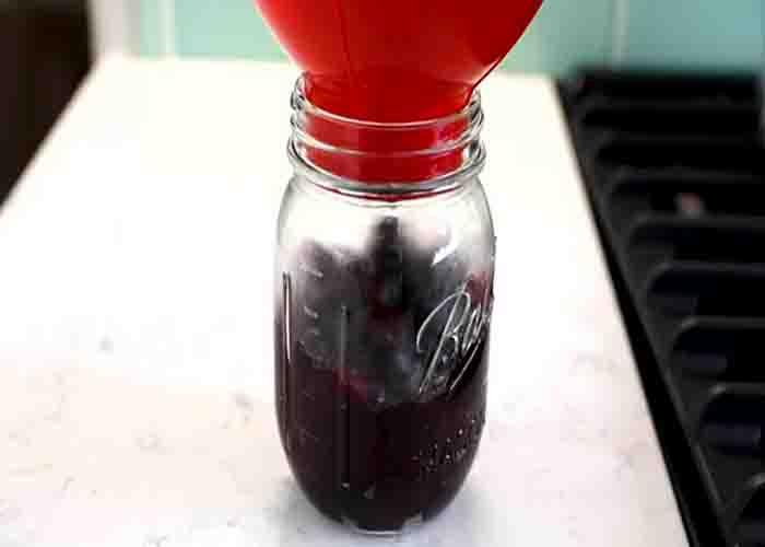 Transferring the homemade blueberry pie filling into a jar