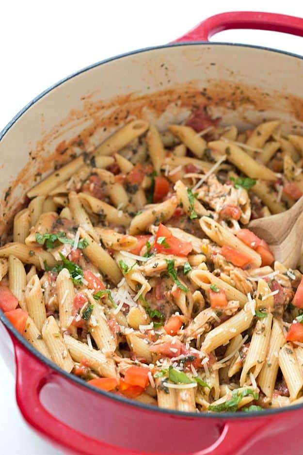 Tuscan chicken with penne pasta in a creamy tomato and spinach sauce topped with fresh basil, ready in twenty minutes