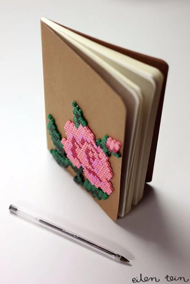 A hardcover notebook with a flower made of perler beads epoxied to the cover, sitting open on a desk, Etsy crafts