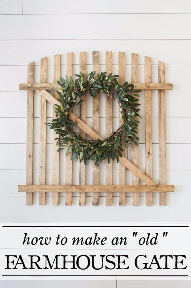 A wide gate built from weathered fence pickets hangs above a fireplace, its gray wash worn back at the edges