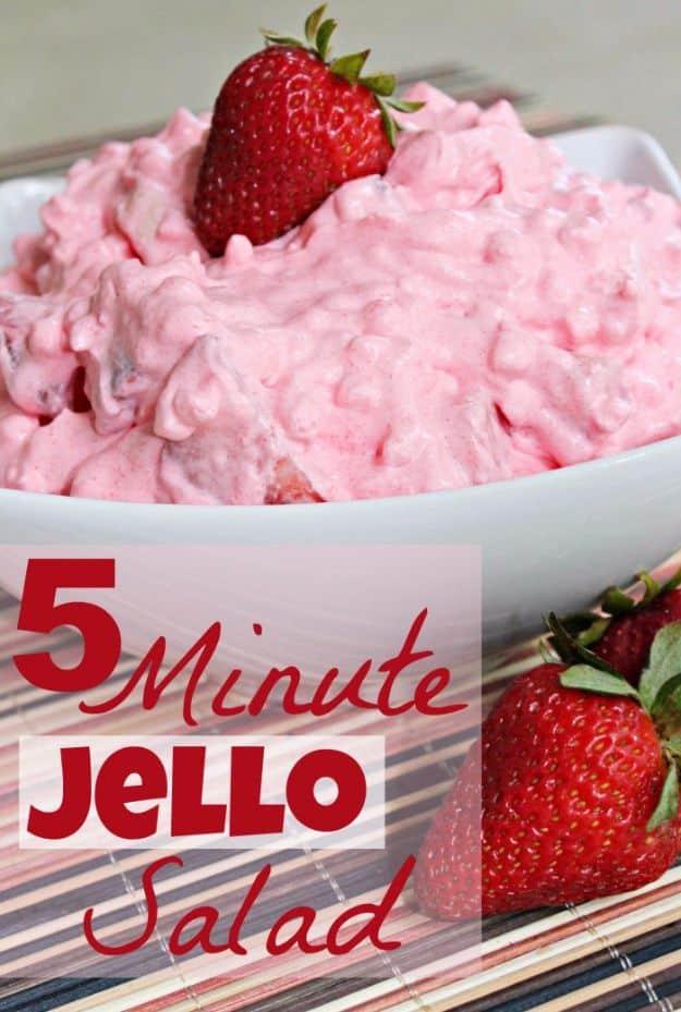 Fluffy pink strawberry jello salad in a white bowl topped with a fresh strawberry, a retro five minute potluck side