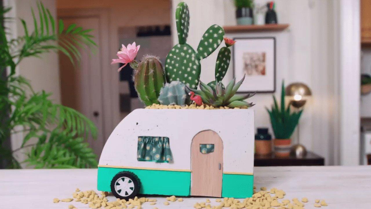 Concrete vintage camper planter, a small white and teal cast cement camper trailer planted with cactus and succulents
