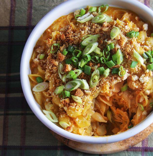 Buffalo chicken mac and cheese in a white bowl topped with toasted breadcrumbs and sliced green onions