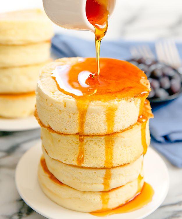 Japanese souffle pancakes stacked tall and jiggly on a white plate with syrup poured over the whole stack