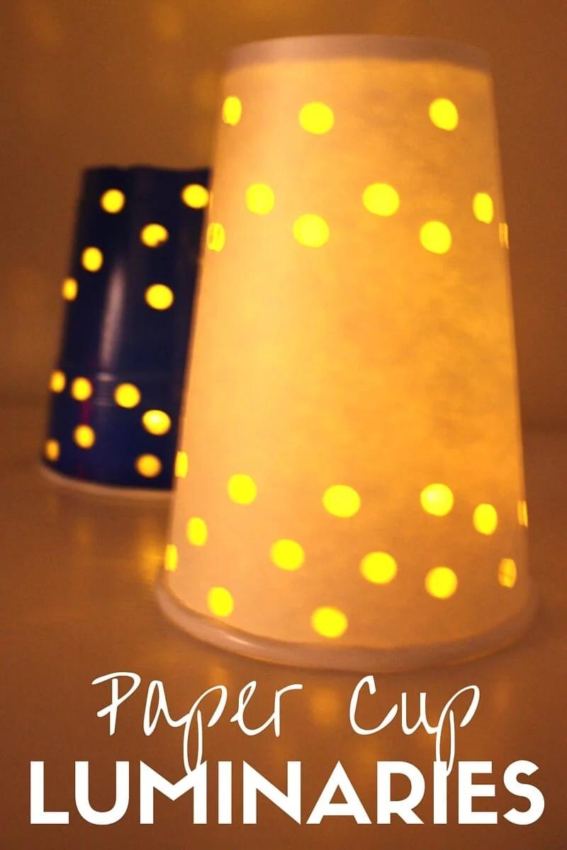 A white paper cup luminary punched with holes glowing yellow over a tea light beside a blue cup, with a title overlay