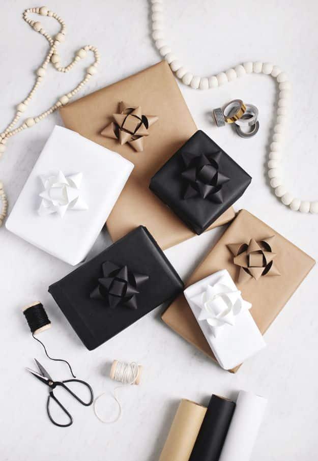 Six parcels in kraft, black and white paper each topped with a folded paper bow, with scissors and bead garlands