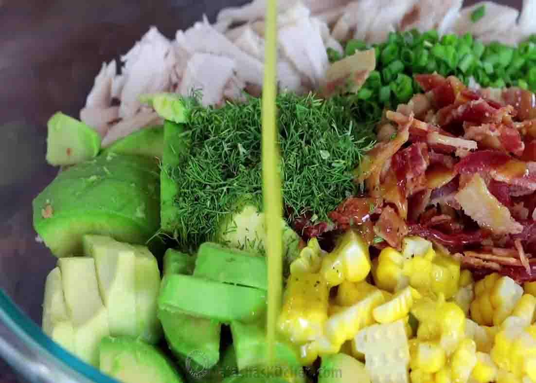 Drizzling the dressing over the avocado chicken salad