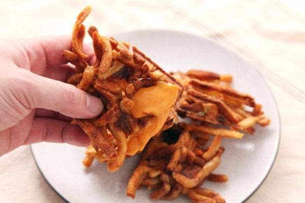 Leftover french fries pressed in a waffle iron into one crisp pull apart slab, torn open across a plate