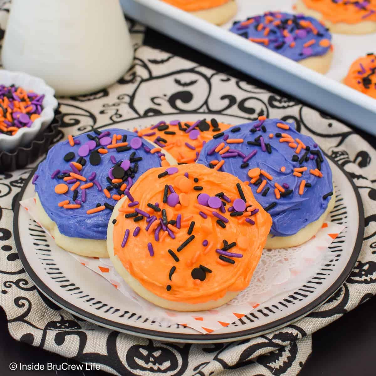 Soft frosted sugar cookies with orange and purple buttercream swirls and Halloween sprinkles on top arranged neatly