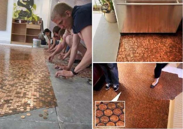 Penny floor being laid, people kneeling to set coins on a bare slab, above panels of the finished copper floor