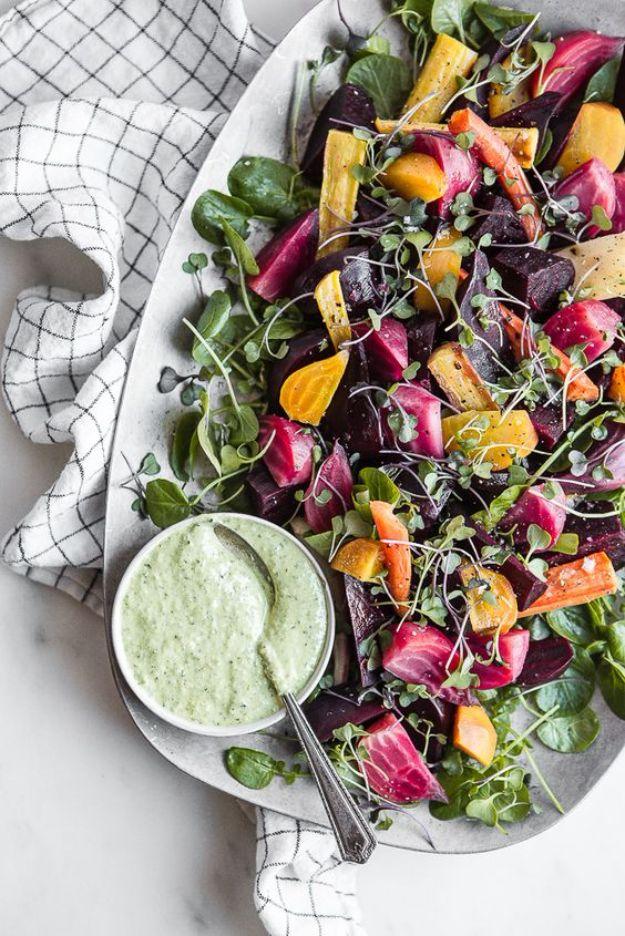 Roasted beet salad on a platter with sliced golden and red beets, greens and green goddess dressing in a bowl