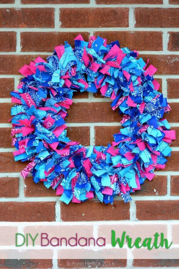 DIY bandana rag wreath craft, pink and turquoise knotted strips on a wire frame against a red brick wall