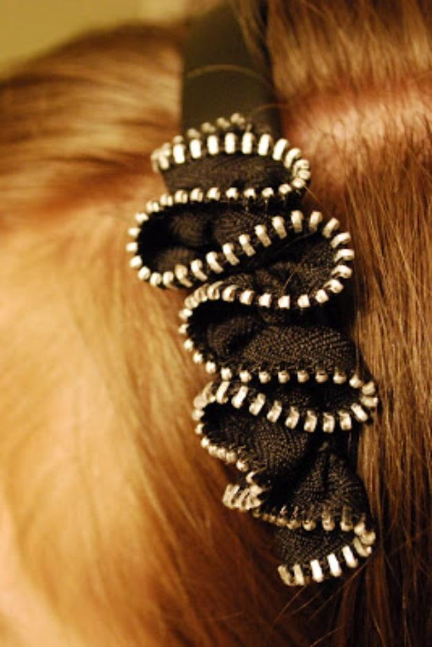 Black zipper ruffle with silver teeth mounted along a headband worn in long auburn hair, photographed from behind