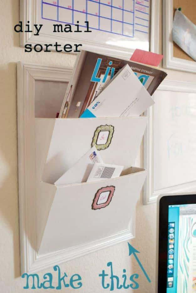 Wall mounted wooden mail pocket set into a white picture frame, holding envelopes and magazines beside a wall calendar