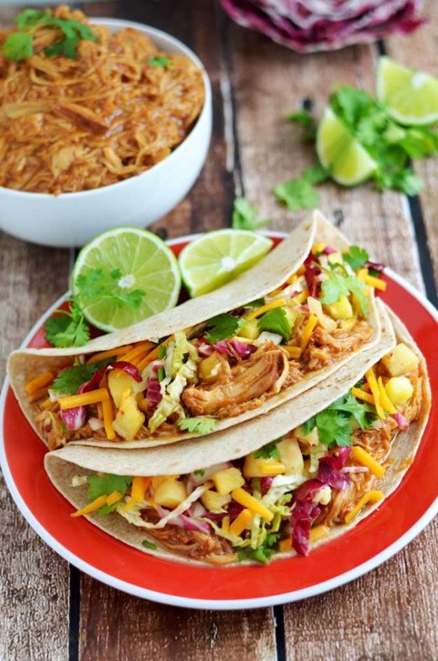 Crock pot Hawaiian BBQ chicken tacos in flour tortillas topped with bright pineapple cabbage slaw ready for the grill