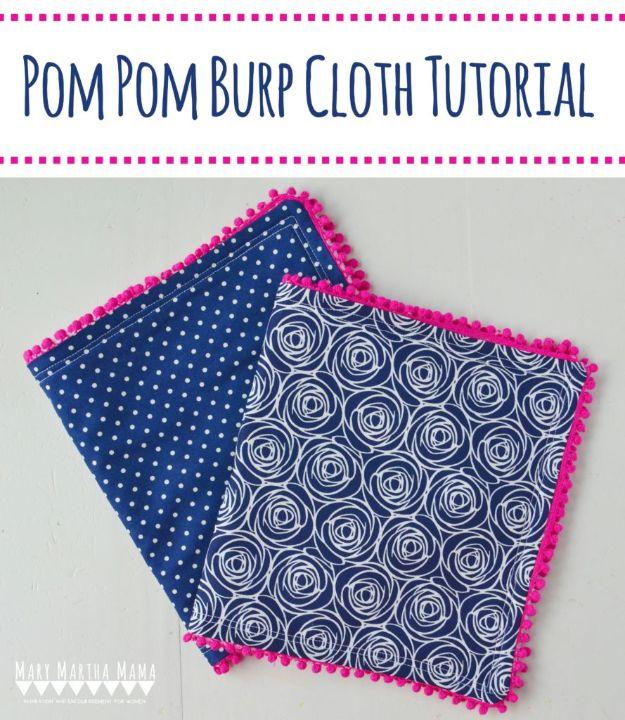 A flannel burp cloth backed in terry with pom pom trim around the edges, folded on a nursery dresser in soft mint