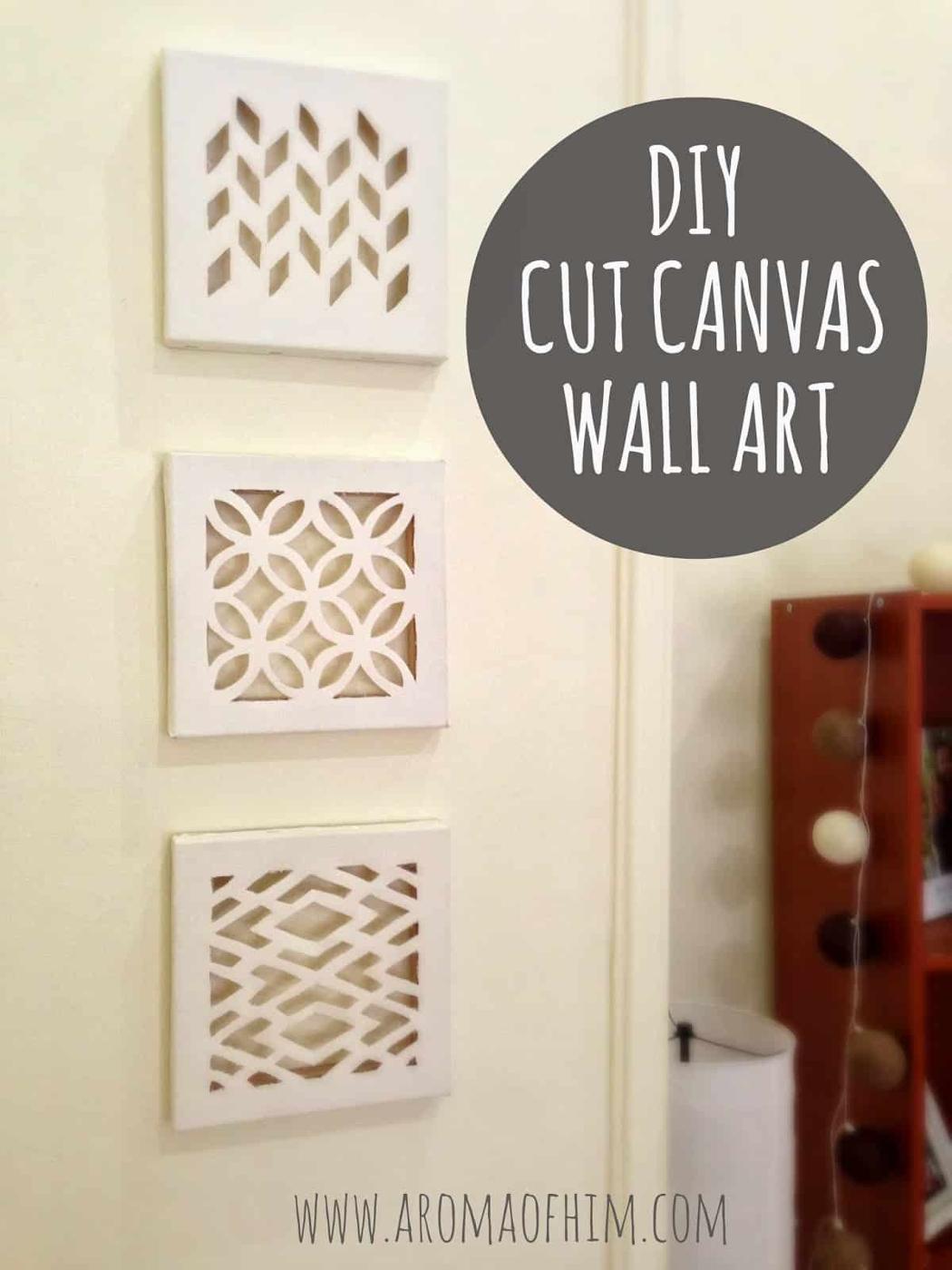 Three white eight inch canvases with geometric patterns cut through the fabric, hung vertically on a cream wall