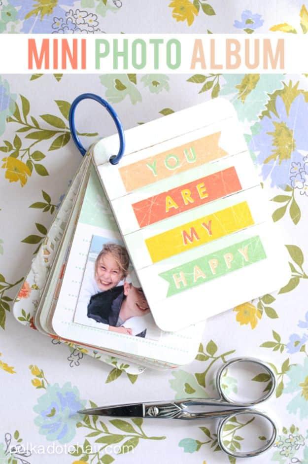 Small ring bound photo album on floral fabric with a YOU ARE MY HAPPY card, photos and scissors alongside