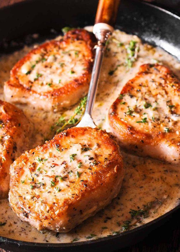 Boneless pork chops in creamy garlic and herb white wine sauce, browned and sprinkled with parsley in a skillet