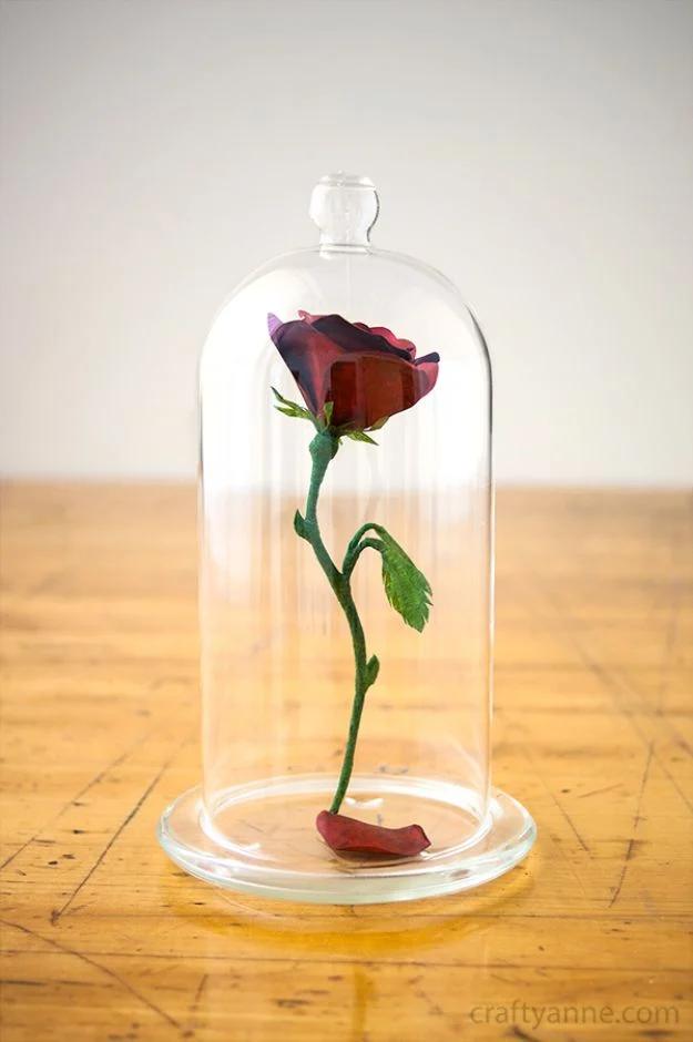 Beauty and the Beast rose centerpiece, a red paper rose floating under a glass cloche on a wooden table