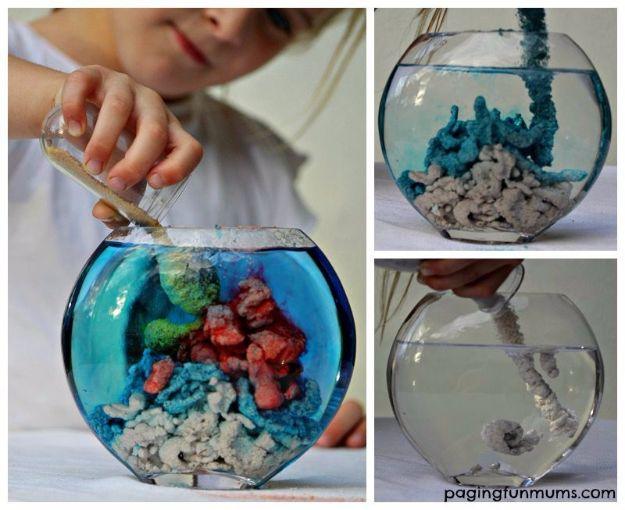 Make magic aqua sand, a child pouring pale sand into a fishbowl of blue water where it stacks into colored underwater shapes