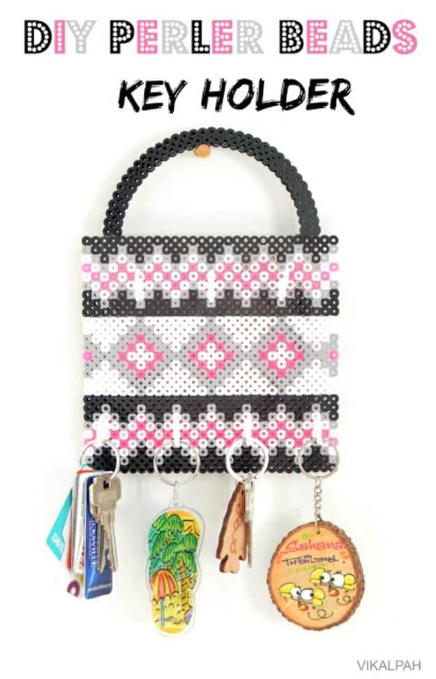 DIY perler bead key holder, a beaded padlock shaped panel in black white and pink with hooks and keys hanging
