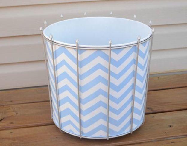 White wire frame trash can lined with a blue and white chevron panel, standing outdoors on weathered wood decking