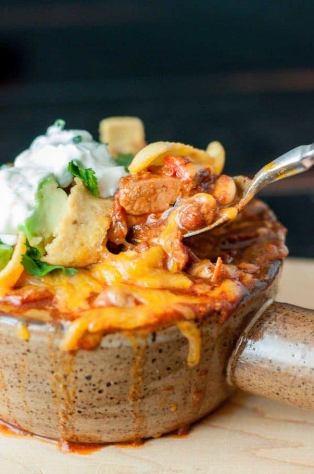 Chorizo chicken chili in a stoneware mug topped with lime cilantro sour cream, avocado and corn chips