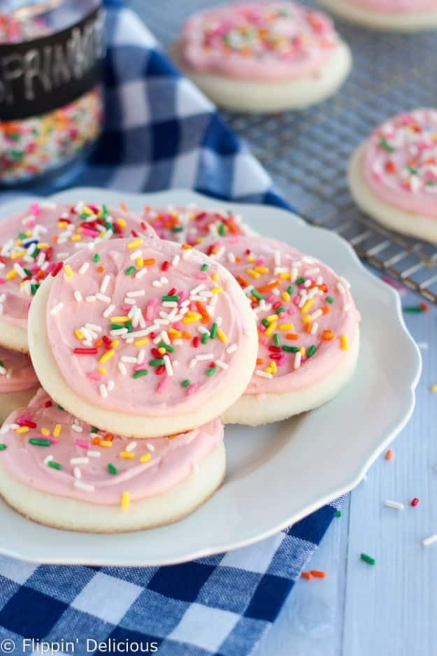 Gluten free soft frosted sugar cookies with thick pink buttercream and rainbow sprinkles over the top